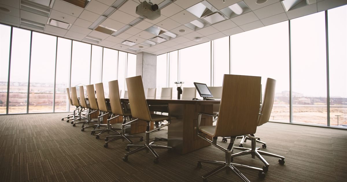 Sala de reuniões vazia com mesa longa e cadeiras
